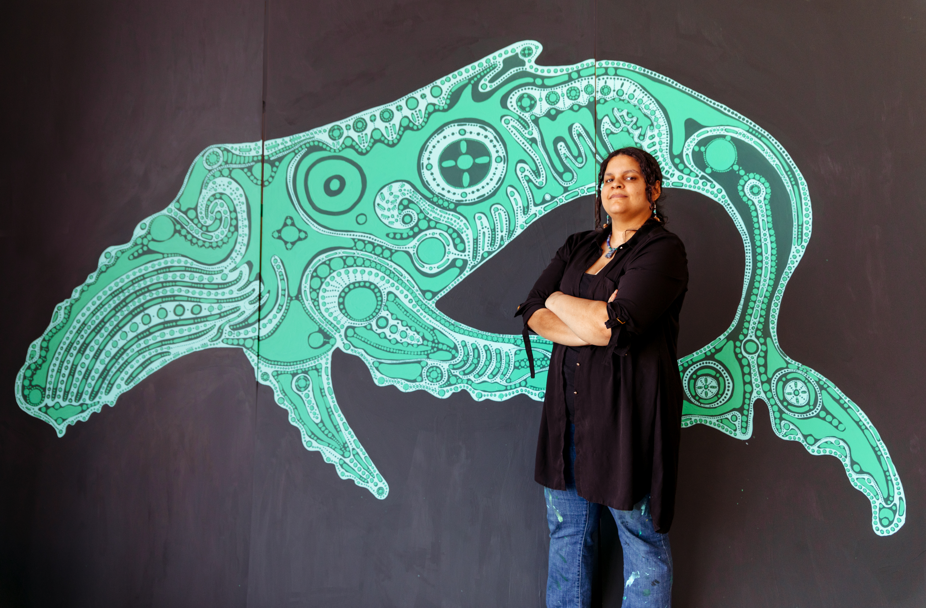 Andromeda Lisle posing in front of her mural, Moshup