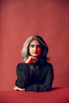 payal kumar headshot, wearing black with red surroundings