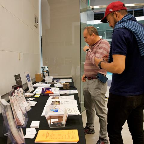 People visiting a table of brochures and offerings at the ed portal