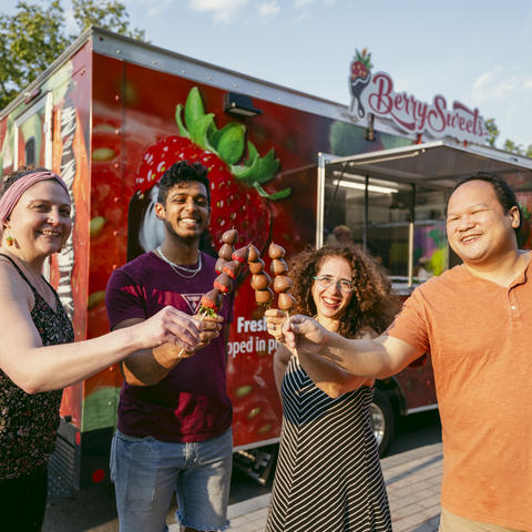 four people stand around with strawberry pops at food truck
