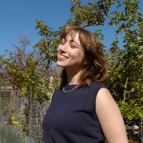 woman smiling upwards towards sky with trees in the background