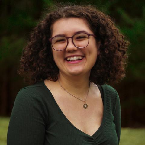 woman wearing glasses poses for picture outdoors smiling