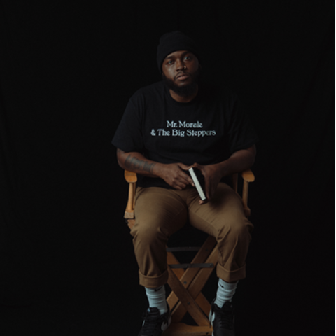 man sits in directors chair with black background