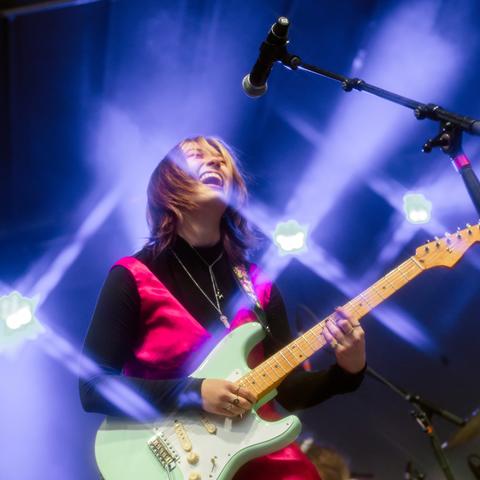 guitarist sings in microphone performing with drums and lights