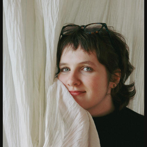Woman posing at camera holding white curtain