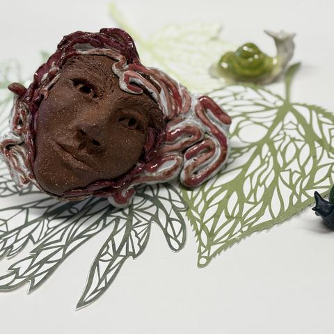 leaf prints on white paper with brown sculpture of a face by artist tashi haig