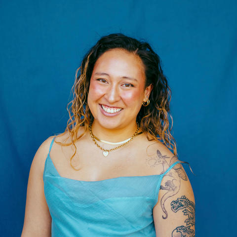 woman in blue dress poses in front of blue background