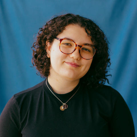 woman wearing glasses poses with blue background