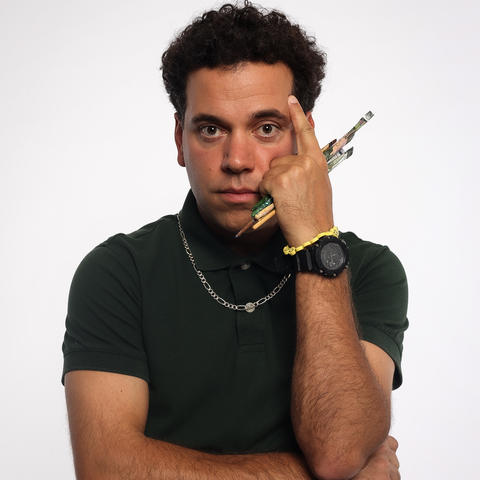 man holds paint brushes with folded arms