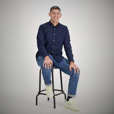 Man sits on stool with white background