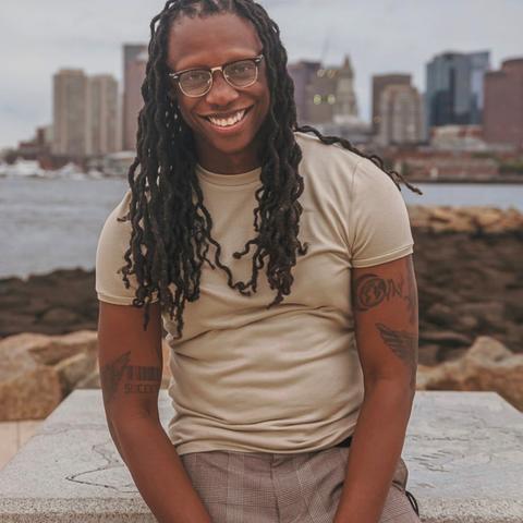 man sits on stoop in front of boston harbor waterfront