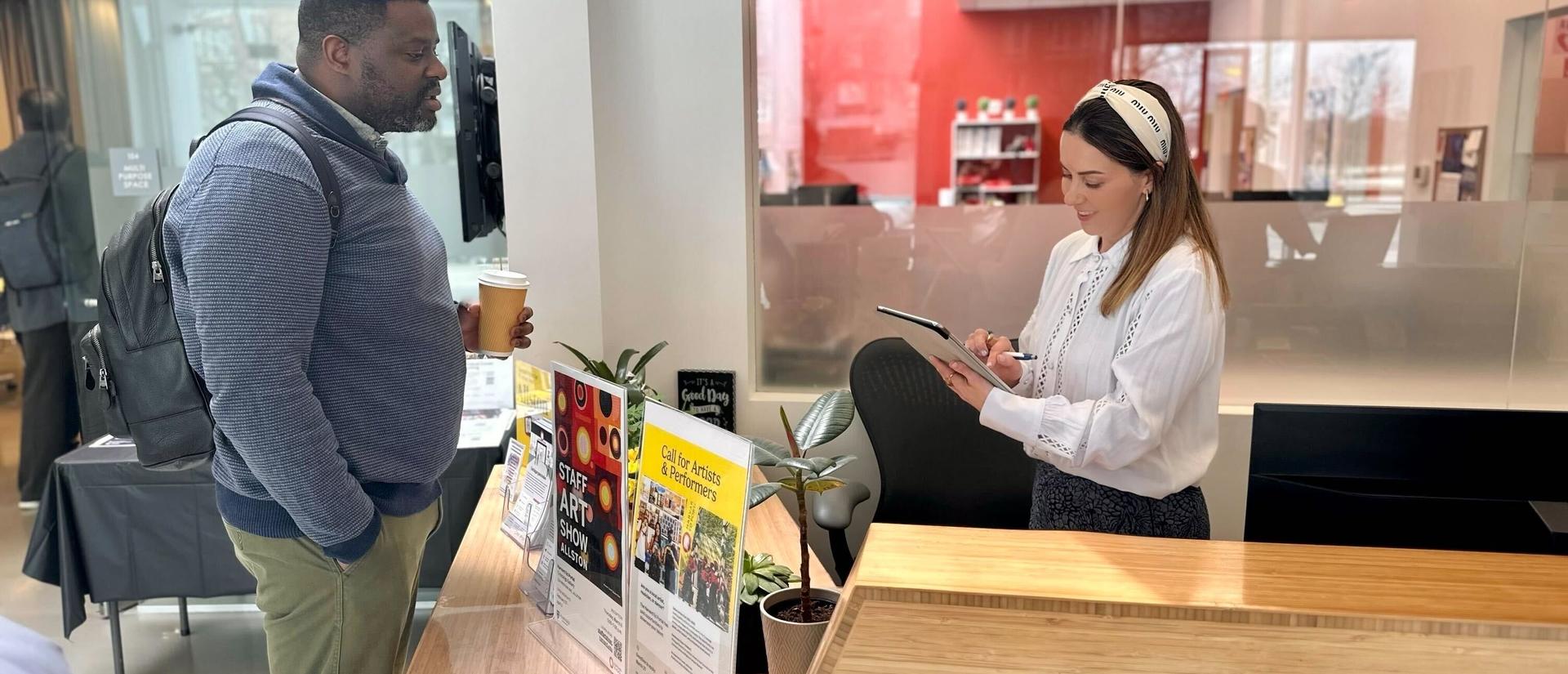 staff greeting guest at front desk at the harvard ed portal